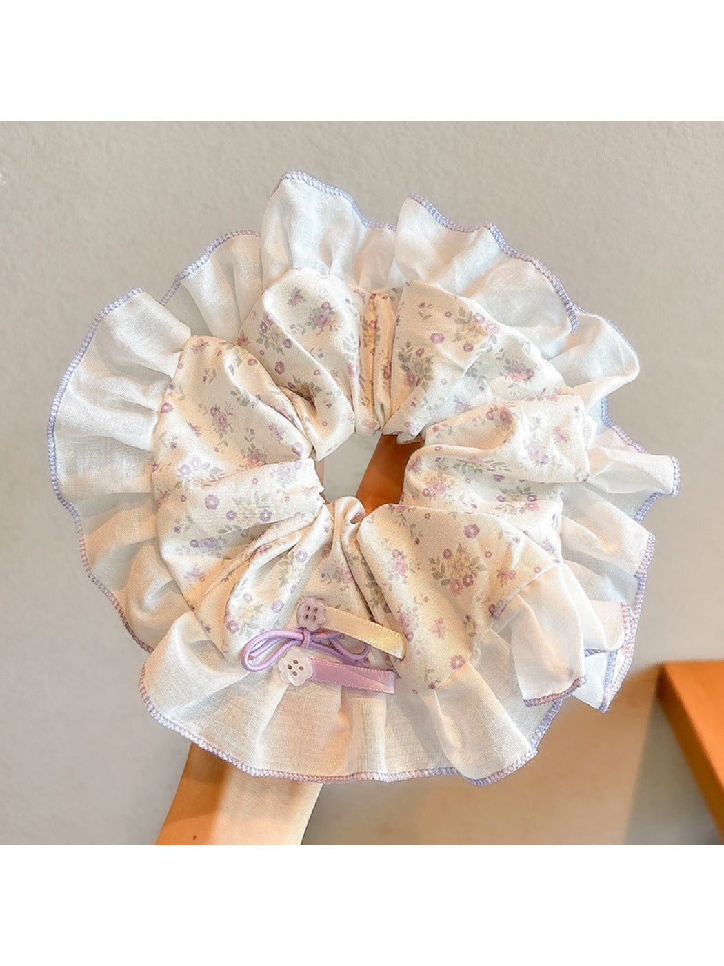 Gifty scrunchie wrapped around a ponytail in brown hair highlighting floral print