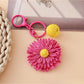 Hand holding the raffia woven sunflower keychain against a plain background