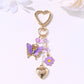 Butterfly heart keychain hanging from a bag zipper with natural outdoor background