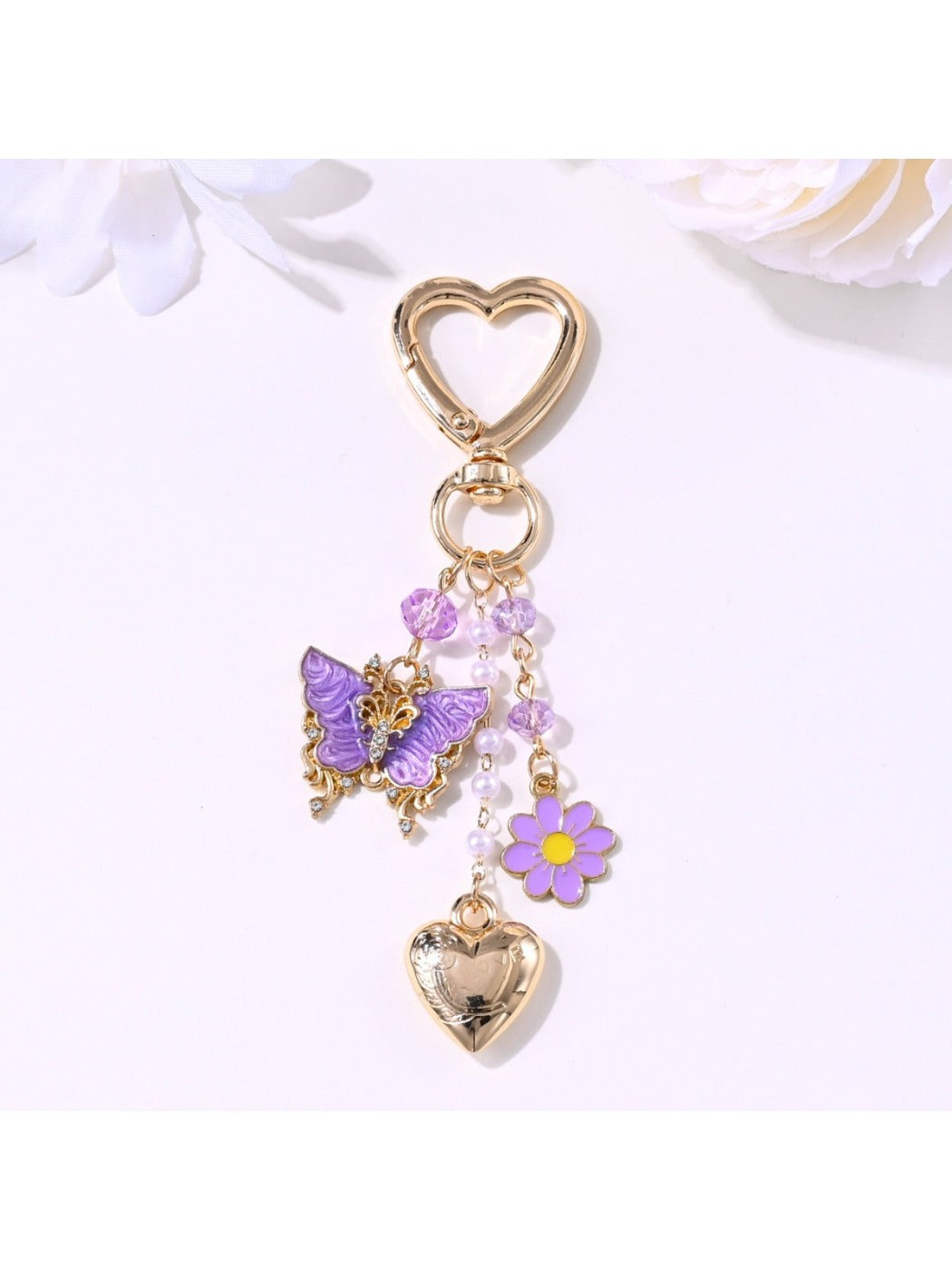 Butterfly heart keychain hanging from a bag zipper with natural outdoor background