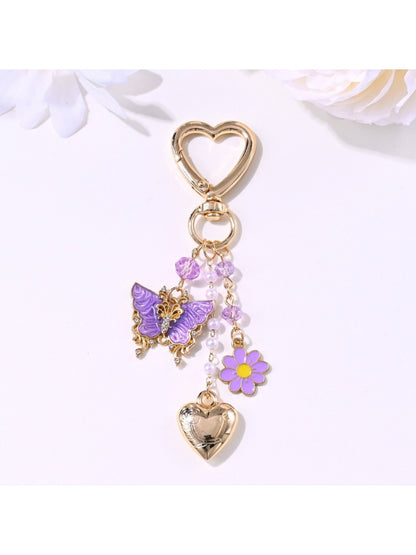 Butterfly heart keychain hanging from a bag zipper with natural outdoor background