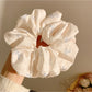 Side view of satin scrunchie featuring subtle bow design in soft fabric
