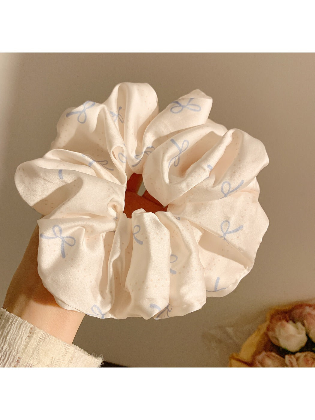 Side view of satin scrunchie featuring subtle bow design in soft fabric