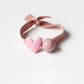 Red hair tie with a small white heart charm on a light fabric