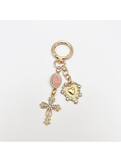 Vintage cross pendant keychain next to a leather wallet and keys