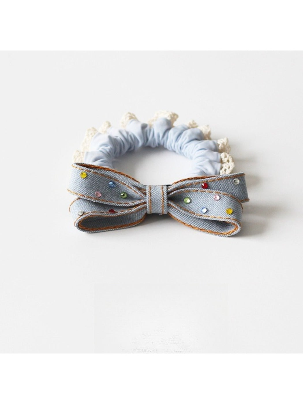 Hand holding a pink bow hair tie showing its elastic band and fabric detail