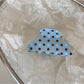 Blue hair clip with white dots shown from top angle