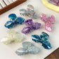 Close-up of iridescent bow hair claw clip showing glossy finish