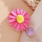 Beau raffia strawberry flower hair clip placed on a wooden surface