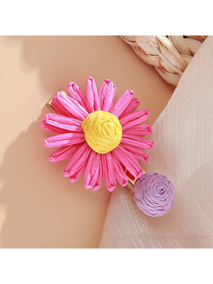 Beau raffia strawberry flower hair clip placed on a wooden surface
