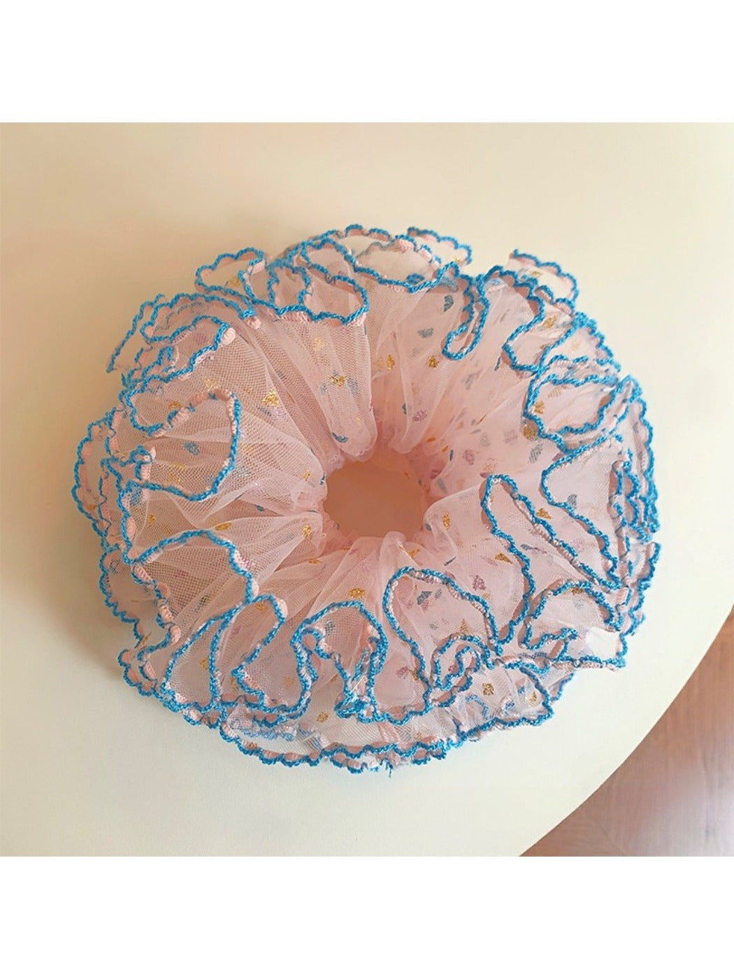 Close-up of a pink four-layer ruffled scrunchie with soft fabric texture