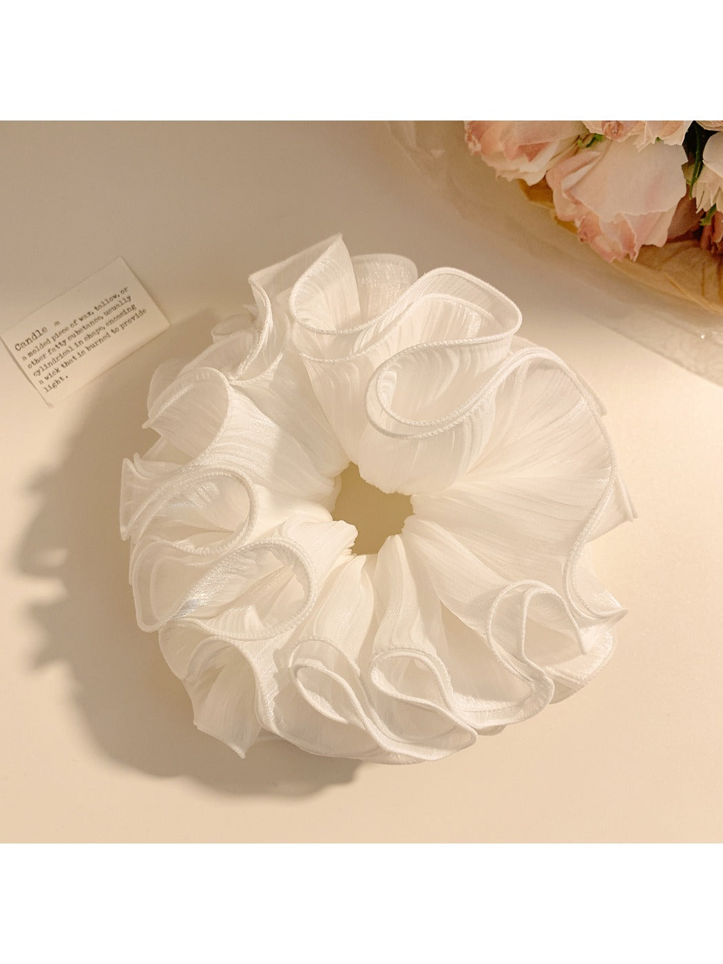 White ruffled scrunchie placed next to matching hair accessories
