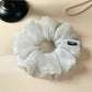 Close-up of a minimalist grey ruched scrunchie on a white background