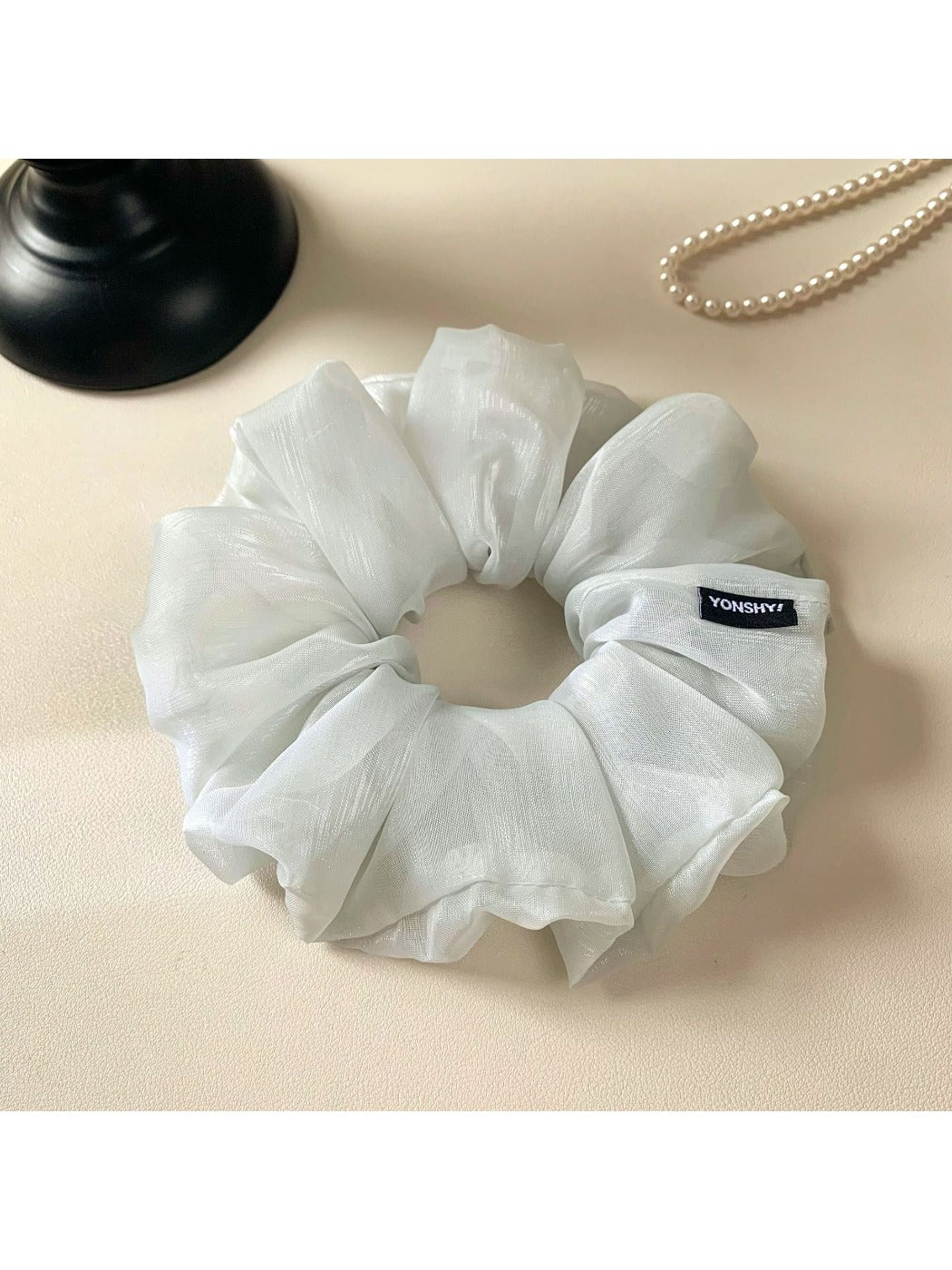 Close-up of a minimalist grey ruched scrunchie on a white background