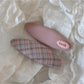 Beau colorful oval hair clip placed on a wooden surface with natural lighting