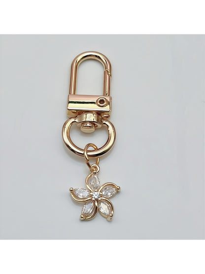 Hand holding Keypus flower-shaped charm keychain with visible gold ring and petals