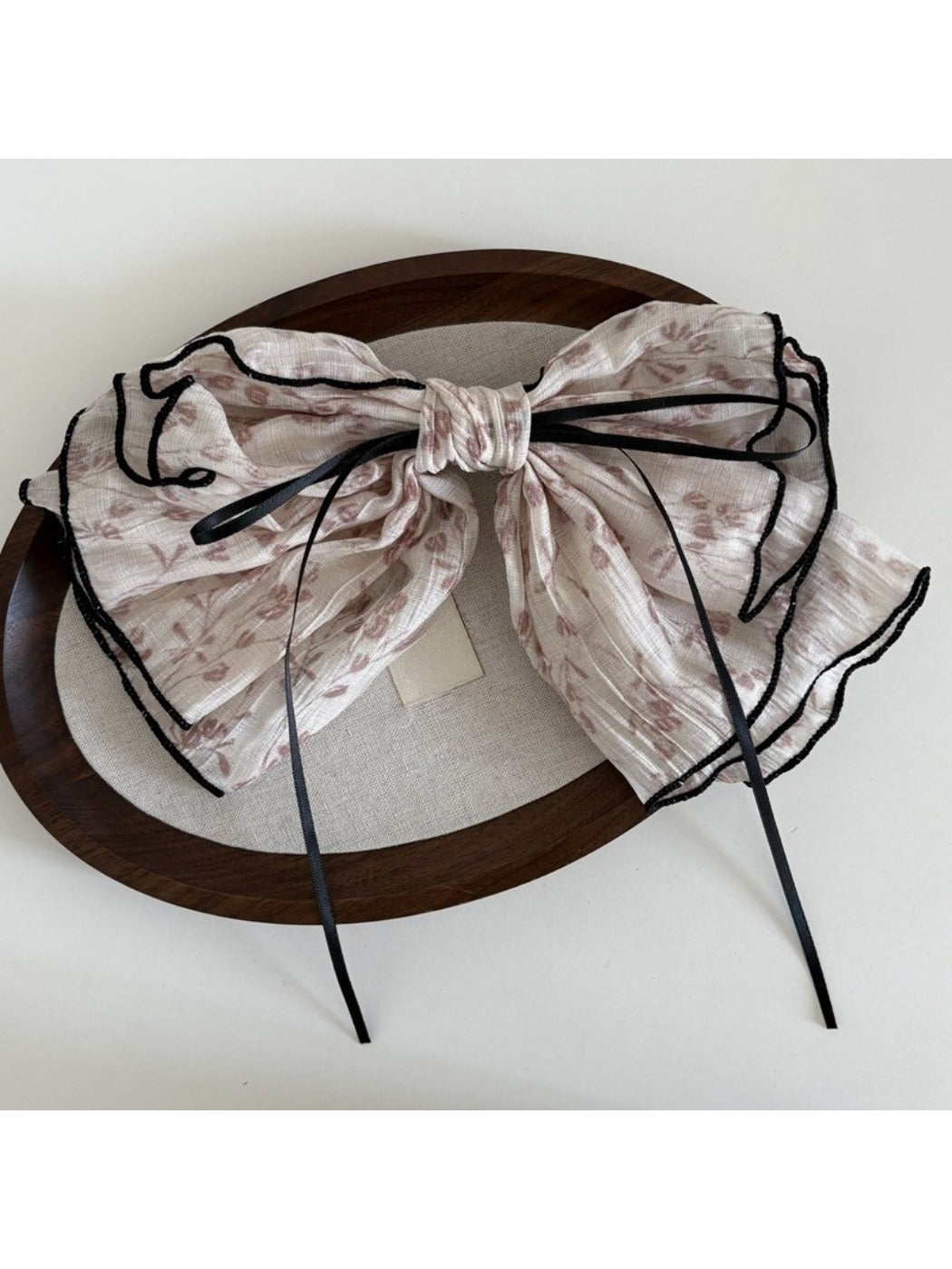 Beau tiny floral bow hair clip held in hand to show size and delicate flower details