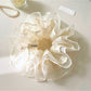 Close-up of Gifty tulle scrunchie with embroidered pink and white flowers