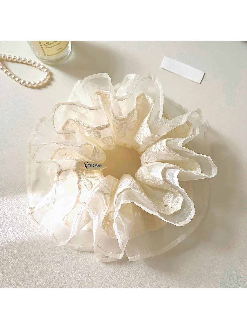 Close-up of Gifty tulle scrunchie with embroidered pink and white flowers