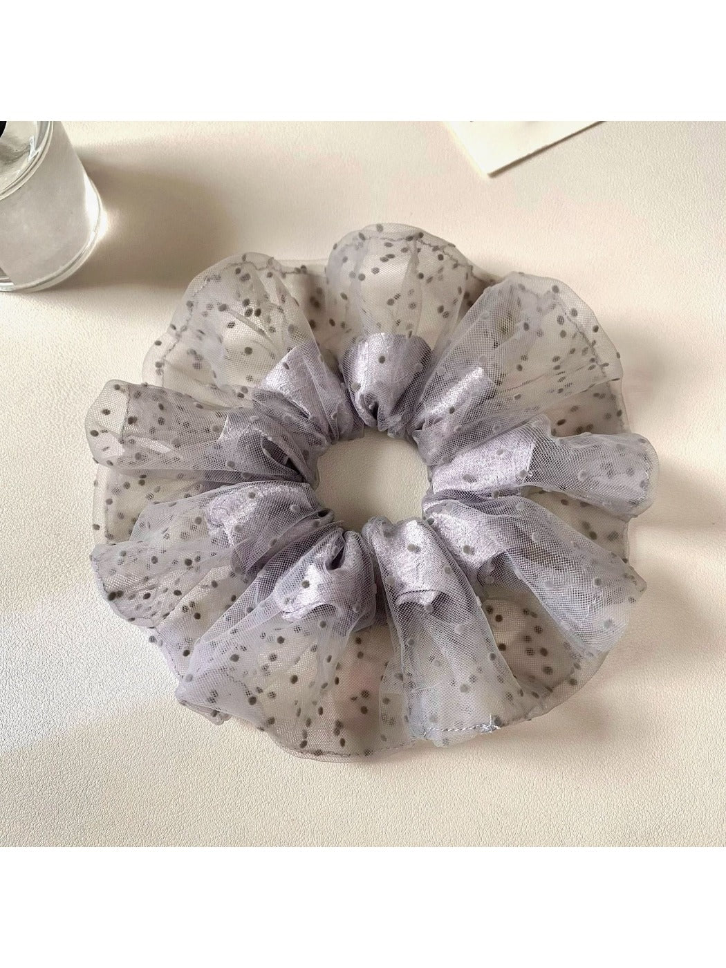Gray polka dot scrunchie wrapped around a ponytail on a model