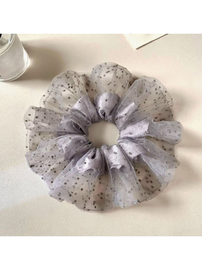 Gray polka dot scrunchie wrapped around a ponytail on a model