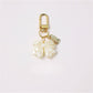 Keypus keychain with pink and white beaded bow charm hanging from a gold keyring