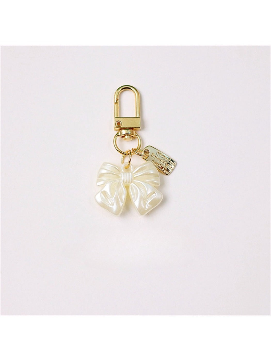 Keypus keychain with pink and white beaded bow charm hanging from a gold keyring