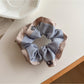 Flat lay of Gifty ruffle scrunchie with color block print on a neutral surface