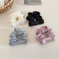 Satin bow scrunchie wrapped around a ponytail on a model with dark hair
