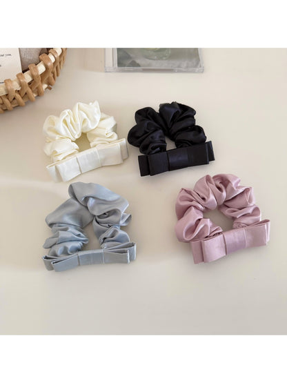 Satin bow scrunchie wrapped around a ponytail on a model with dark hair