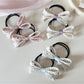 Close-up of Gifty hair tie with pink bow and floral print on fabric
