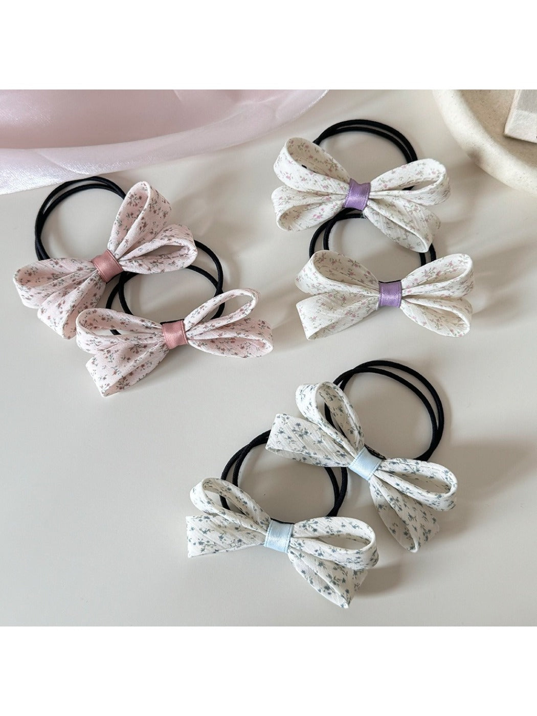 Close-up of Gifty hair tie with pink bow and floral print on fabric
