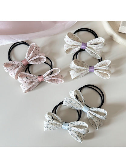 Close-up of Gifty hair tie with pink bow and floral print on fabric