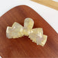 Beau bow shaped hair claw clip in beige with metal spring visible