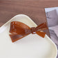 Beau bow-shaped hair clip placed on a wooden surface with natural lighting