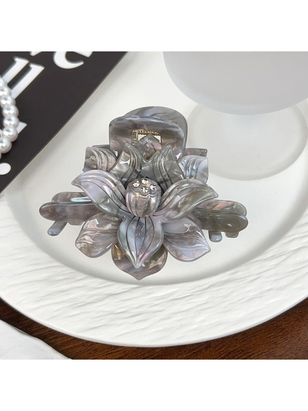 Beau lotus hair claw clip resting on a wooden surface