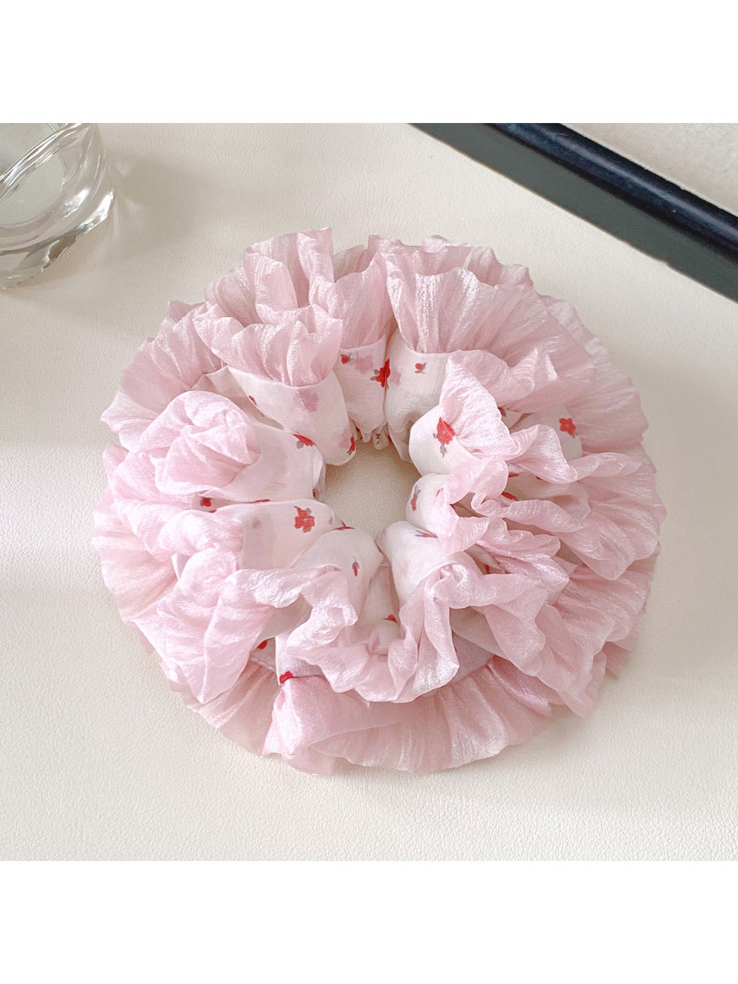 Pink scrunchie styled on a wrist against a white background