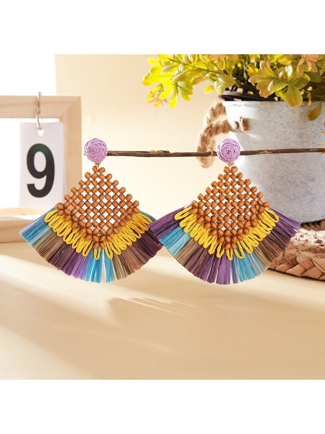 Vintage square raffia drop earrings hanging from a jewelry stand with natural lighting