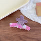 Beau flower shaped claw clip next to matching pastel accessories