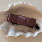 Beau vintage bow hair clip photographed with natural lighting on wooden surface