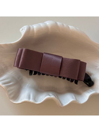 Beau vintage bow hair clip photographed with natural lighting on wooden surface