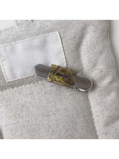 Beau vintage flat hair clip placed on textured fabric background