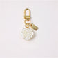 Flat lay of Keypus beaded bow charm keychain with gold ring and vibrant beads on fabric