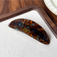 Beau hair clip in tortoiseshell acetate resting on a wooden surface