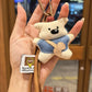 Fabric bear keychain attached to a set of keys on a wooden surface