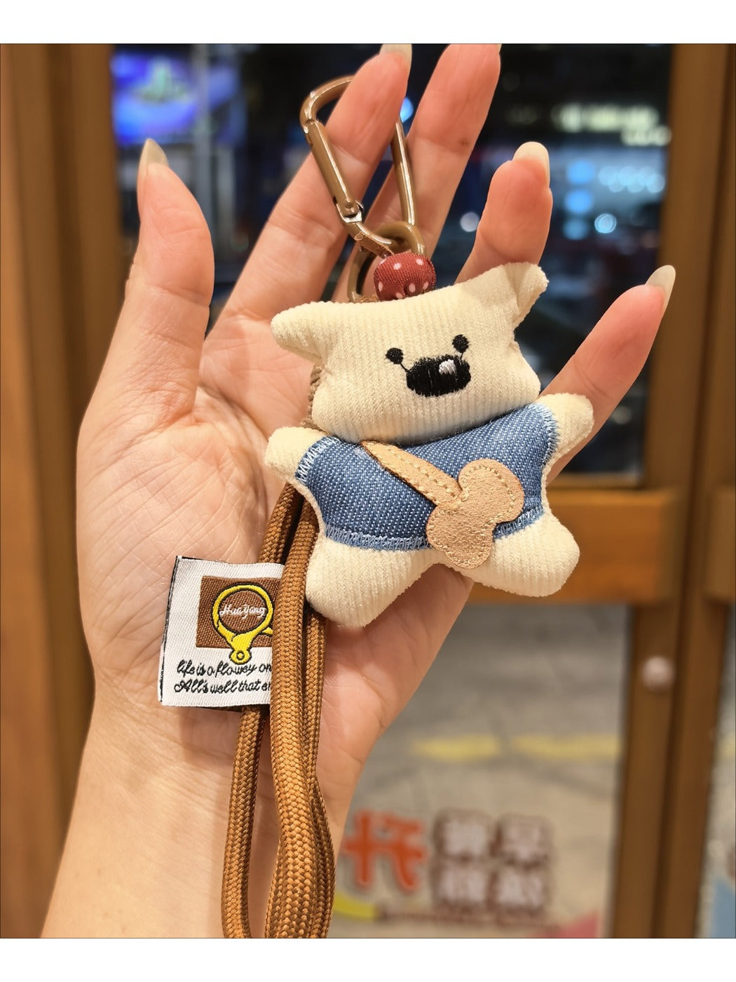 Fabric bear keychain attached to a set of keys on a wooden surface