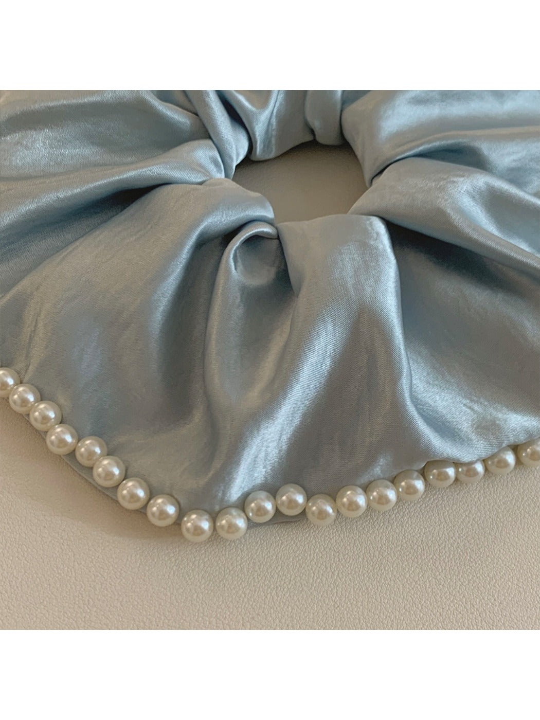 Gifty satin scrunchie with pearl beads displayed on a wooden surface
