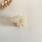 Beau flower hair clip held in hand to show scale and natural material texture
