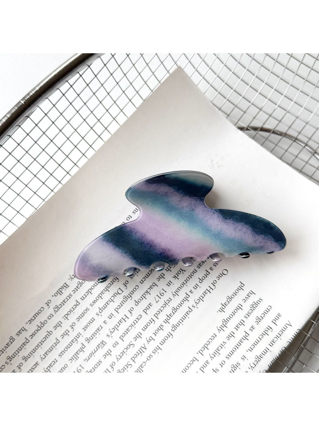 Beau hair claw clip resting on fabric surface with light reflection