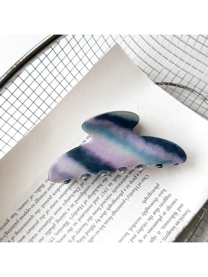 Beau hair claw clip resting on fabric surface with light reflection